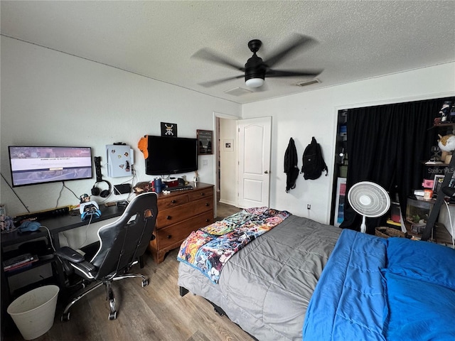 bedroom featuring visible vents, a textured ceiling, wood finished floors, and a ceiling fan