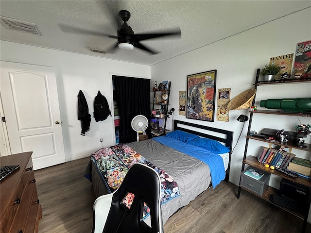 bedroom featuring ceiling fan, wood finished floors, visible vents, and a textured ceiling