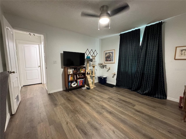 interior space with a ceiling fan, wood finished floors, baseboards, and a textured ceiling