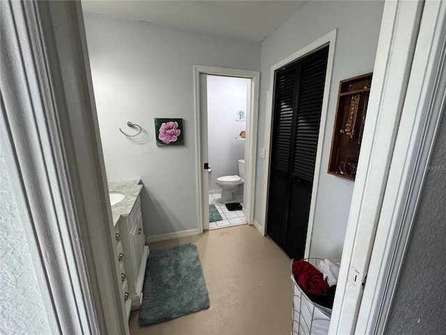 bathroom with vanity, baseboards, finished concrete floors, a closet, and toilet