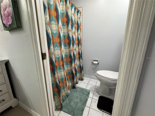 bathroom with curtained shower, toilet, vanity, and baseboards