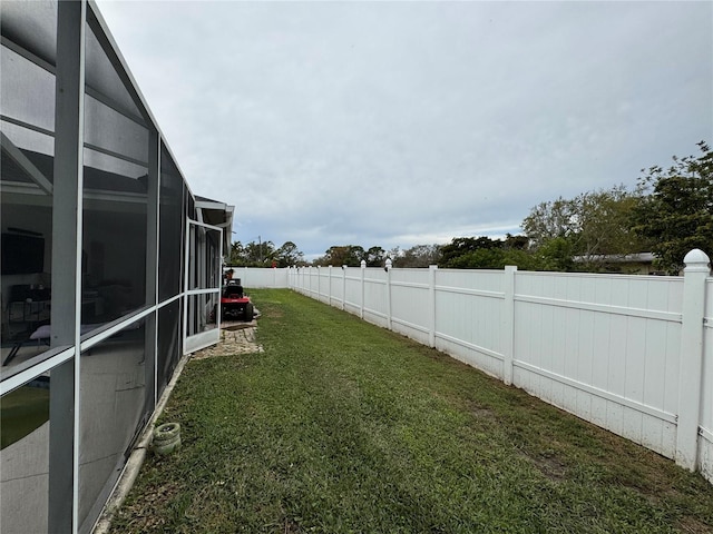 view of yard featuring glass enclosure and a fenced backyard