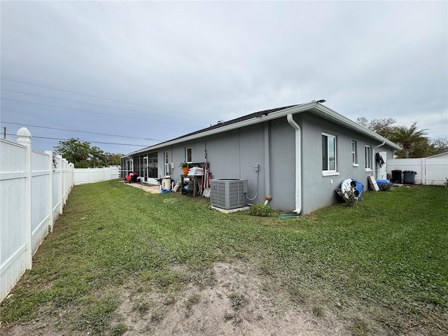 view of home's exterior featuring central air condition unit, a lawn, a fenced backyard, and stucco siding