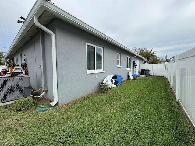 view of side of home with cooling unit, a lawn, a fenced backyard, and stucco siding