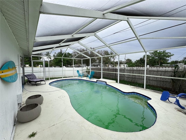 view of pool featuring glass enclosure, a patio, a fenced backyard, and a fenced in pool