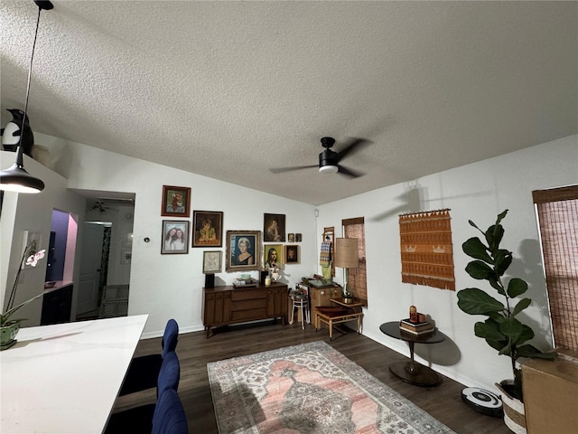 interior space with a ceiling fan, a textured ceiling, baseboards, dark wood-style flooring, and vaulted ceiling