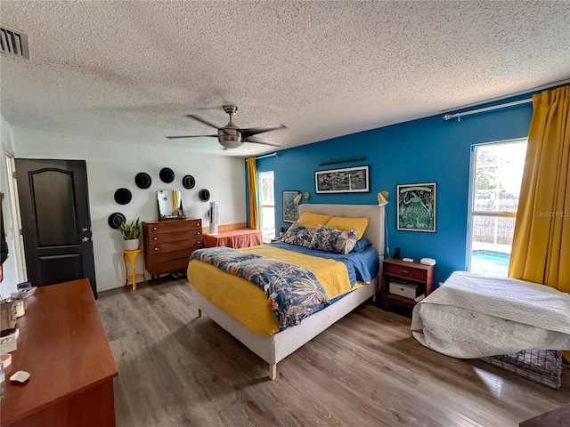 bedroom featuring a textured ceiling, wood finished floors, visible vents, and ceiling fan