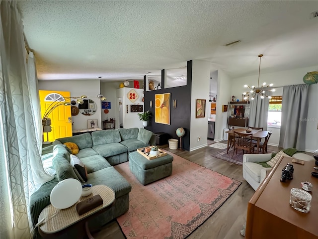 living room featuring a notable chandelier, wood finished floors, a textured ceiling, and visible vents