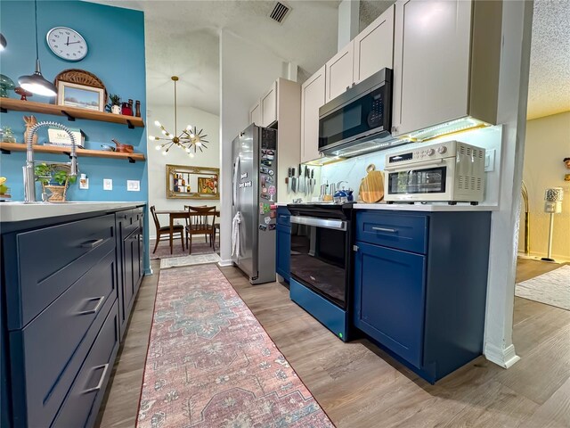 kitchen with blue cabinets, vaulted ceiling, visible vents, an inviting chandelier, and appliances with stainless steel finishes