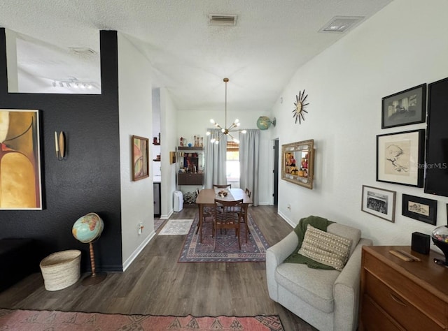 dining area with wood finished floors, an inviting chandelier, baseboards, lofted ceiling, and visible vents