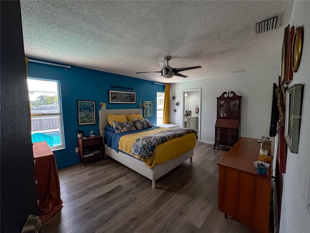 bedroom featuring wood finished floors, visible vents, a textured ceiling, and ceiling fan