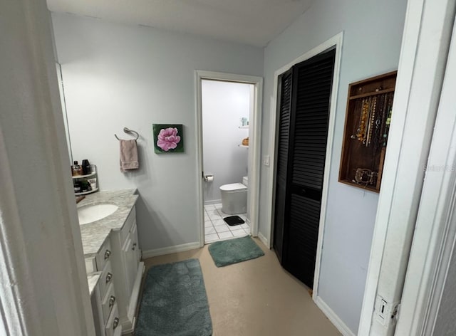 bathroom with baseboards, vanity, a closet, and toilet