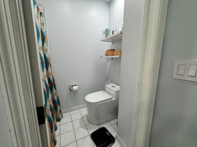 bathroom with tile patterned flooring, toilet, and baseboards
