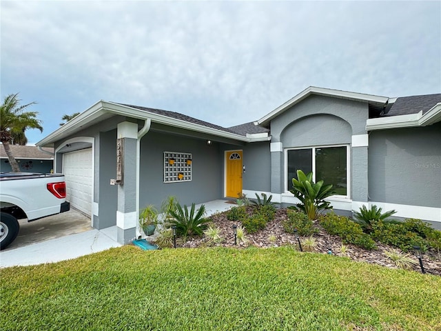 ranch-style home with stucco siding, an attached garage, and a front yard