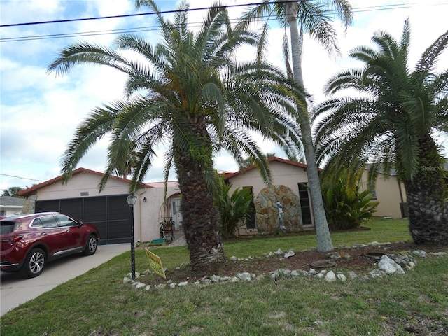 view of front of home with driveway, a garage, a front lawn, and stucco siding