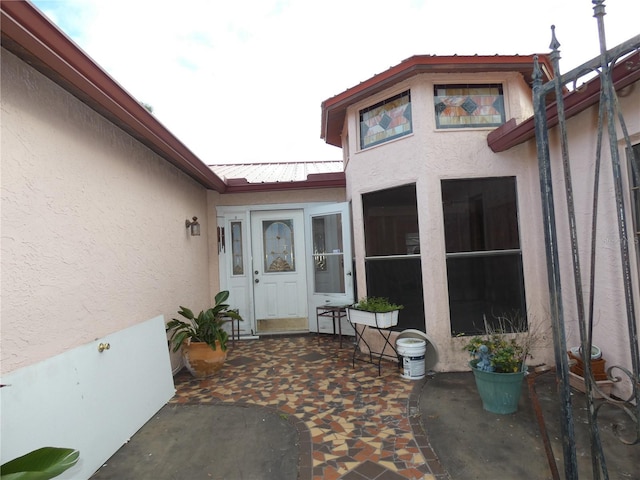 doorway to property featuring metal roof, a patio, and stucco siding