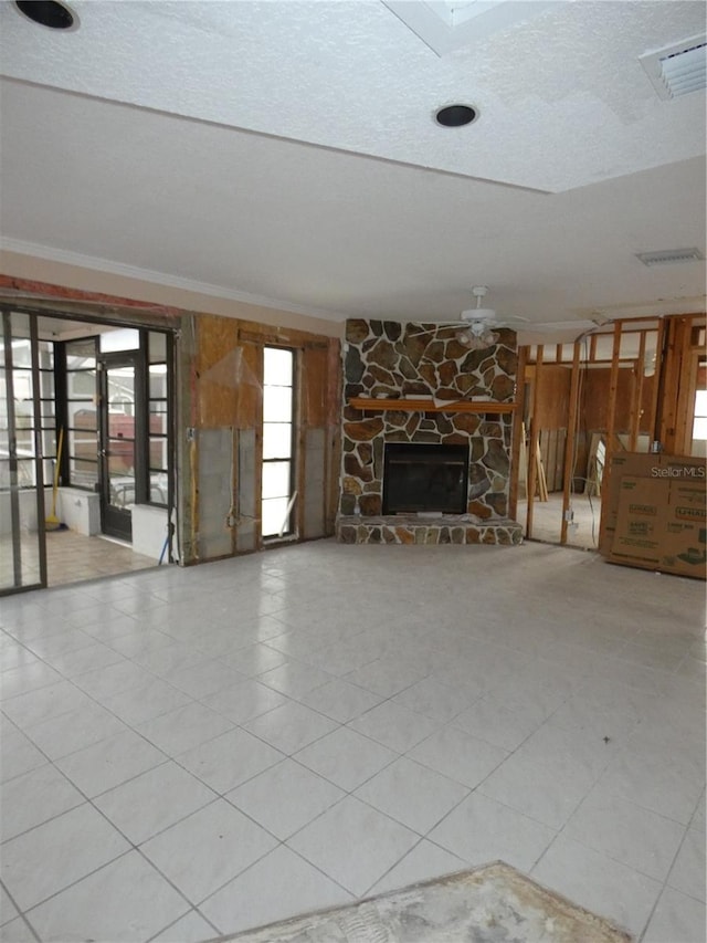 7308 Mako Dr, Hudson, FL 34667 - unfurnished living room featuring ornamental molding, visible vents, a stone fireplace, and a textured ceiling