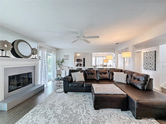 living room with visible vents, wood finished floors, a wealth of natural light, and a glass covered fireplace