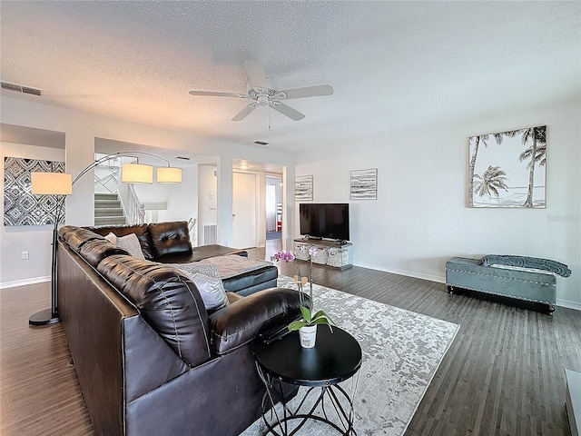 living room with dark wood finished floors, visible vents, a textured ceiling, baseboards, and stairs