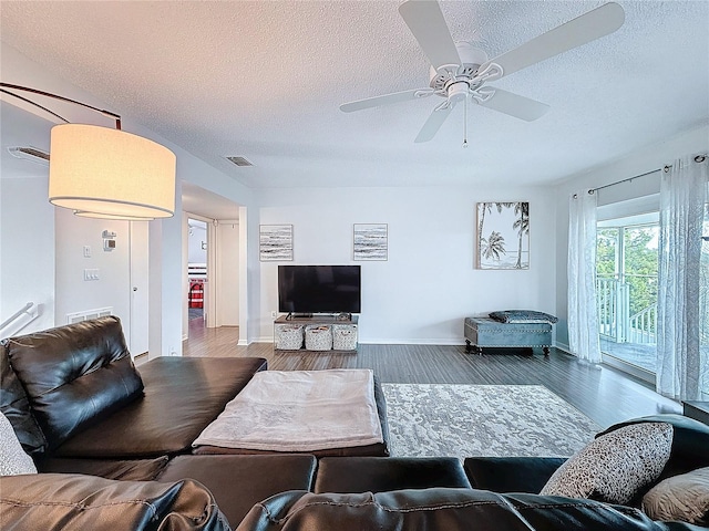 living room featuring ceiling fan, a textured ceiling, visible vents, and wood finished floors