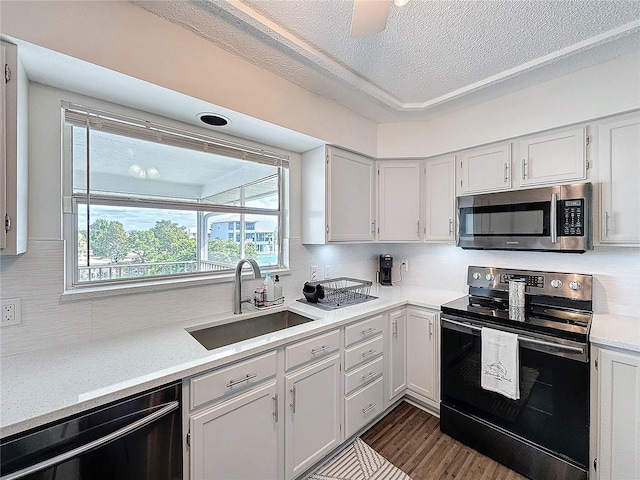 kitchen featuring range with electric cooktop, a sink, light countertops, dishwasher, and stainless steel microwave