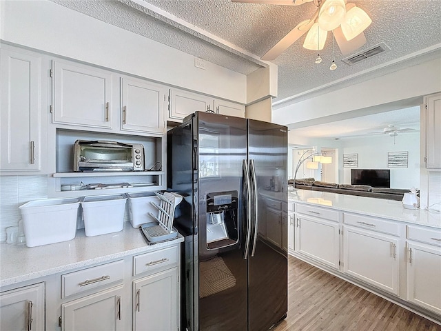 kitchen with white cabinetry, visible vents, light countertops, and stainless steel fridge with ice dispenser