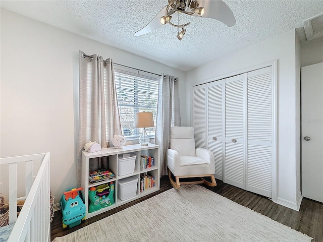 bedroom with a textured ceiling, dark wood-style flooring, visible vents, a ceiling fan, and a closet