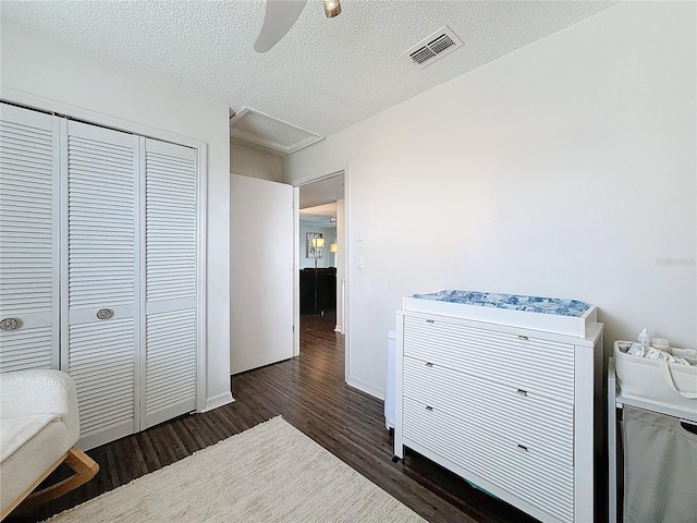 bedroom with a textured ceiling, dark wood-type flooring, visible vents, a ceiling fan, and a closet