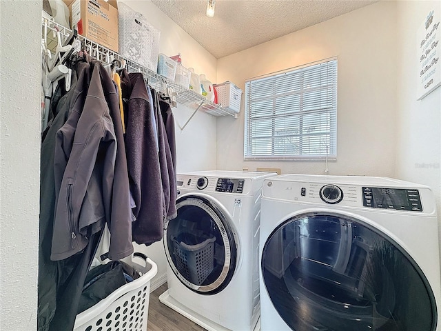 clothes washing area with laundry area, a textured ceiling, wood finished floors, and washing machine and clothes dryer