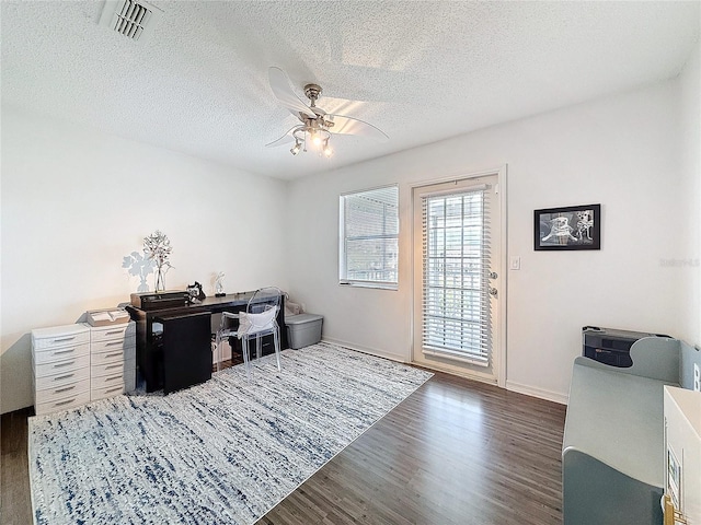 office space featuring a textured ceiling, visible vents, dark wood finished floors, and a ceiling fan