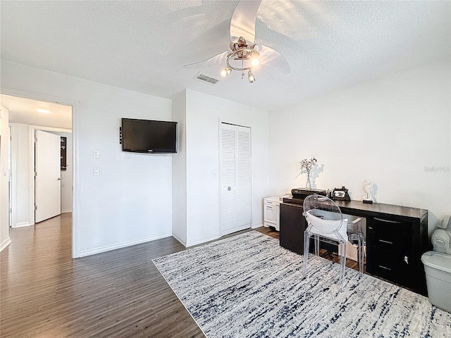 home office featuring baseboards, visible vents, dark wood finished floors, a ceiling fan, and a textured ceiling