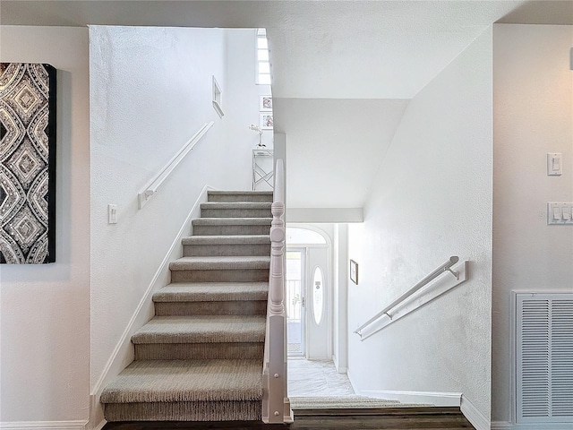 staircase featuring wood finished floors, visible vents, and baseboards