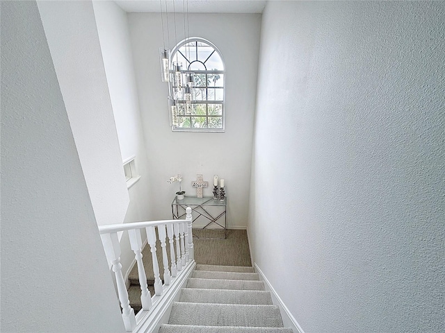 stairs with carpet, a textured wall, and baseboards