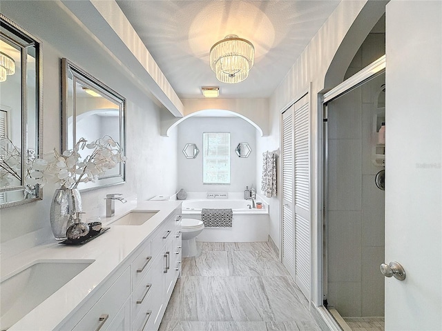 full bath with double vanity, a closet, toilet, a garden tub, and a sink