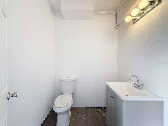 half bathroom featuring marble finish floor, vanity, and toilet