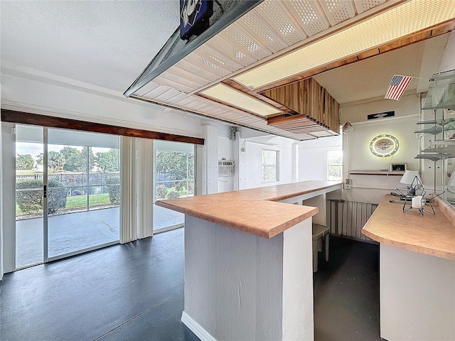 kitchen with light countertops, concrete floors, a peninsula, and a kitchen bar