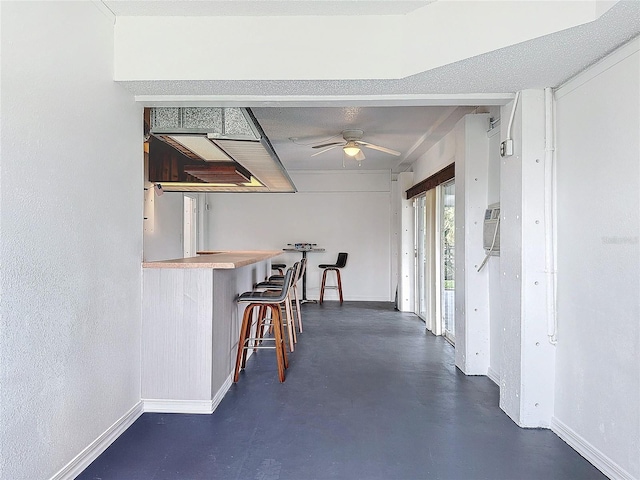 interior space featuring finished concrete floors, ceiling fan, and baseboards