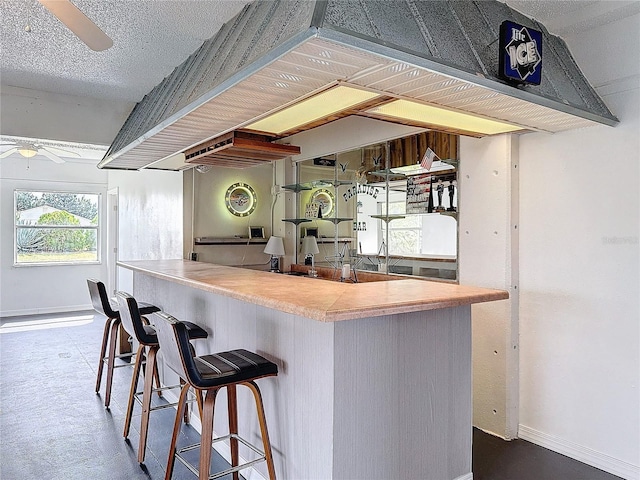 kitchen with a textured ceiling, a ceiling fan, and baseboards