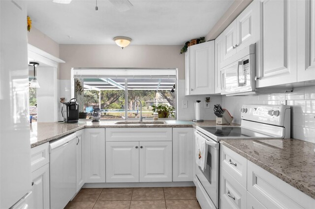 kitchen featuring white appliances, white cabinets, a sink, and light tile patterned flooring