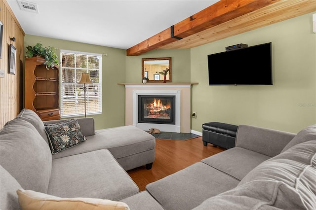 living room with light wood-type flooring, visible vents, beam ceiling, and a glass covered fireplace