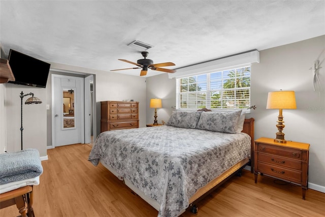 bedroom with ceiling fan, light wood finished floors, visible vents, and baseboards