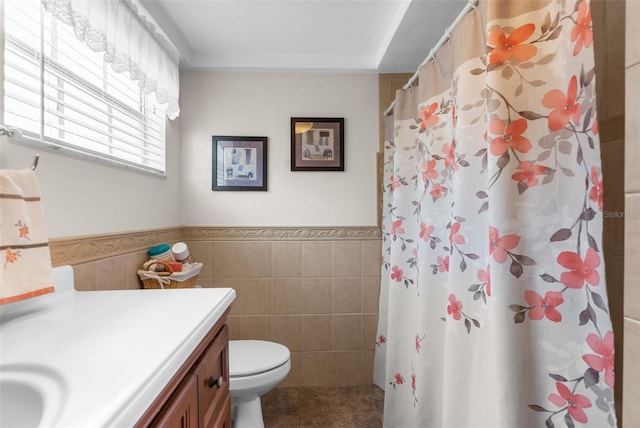 full bathroom featuring wainscoting, toilet, tile patterned flooring, vanity, and tile walls