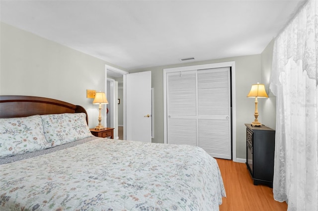 bedroom with a closet, light wood-type flooring, and visible vents