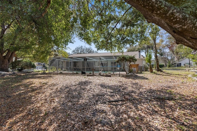 back of property with glass enclosure and a pool