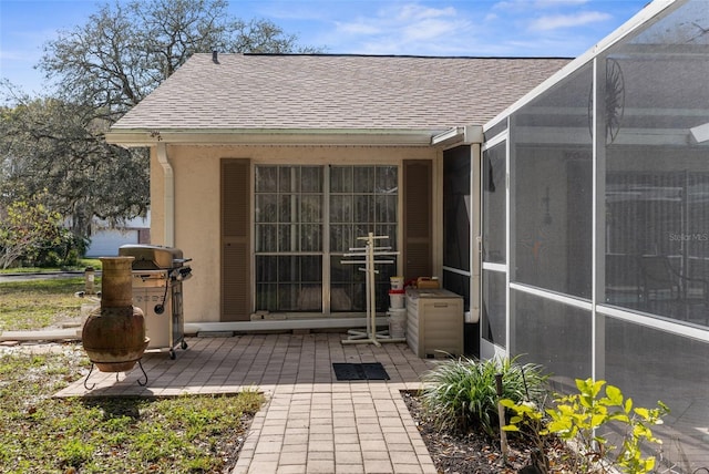 doorway to property featuring a patio area and a shingled roof