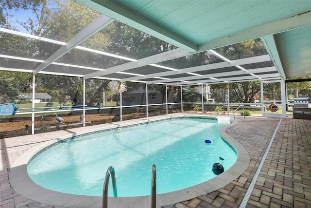 outdoor pool featuring glass enclosure and a patio