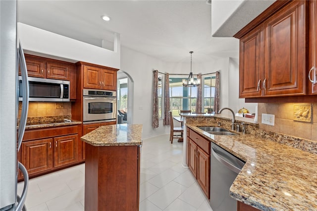 kitchen featuring a sink, arched walkways, appliances with stainless steel finishes, light stone countertops, and a chandelier