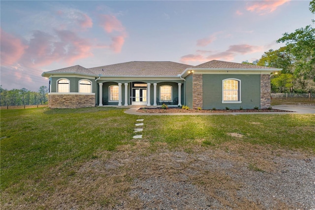 view of front of property with a lawn, stone siding, and stucco siding