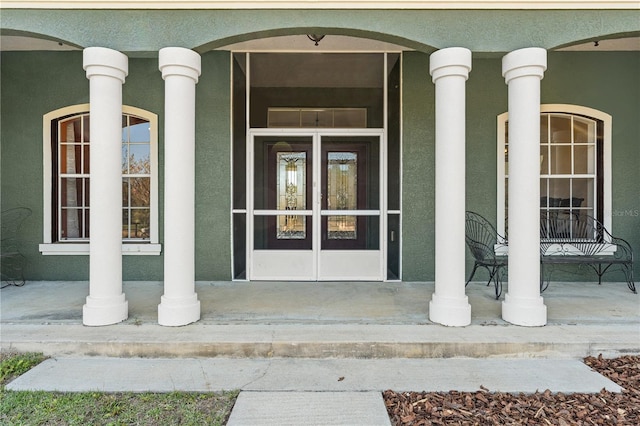 property entrance with covered porch and stucco siding