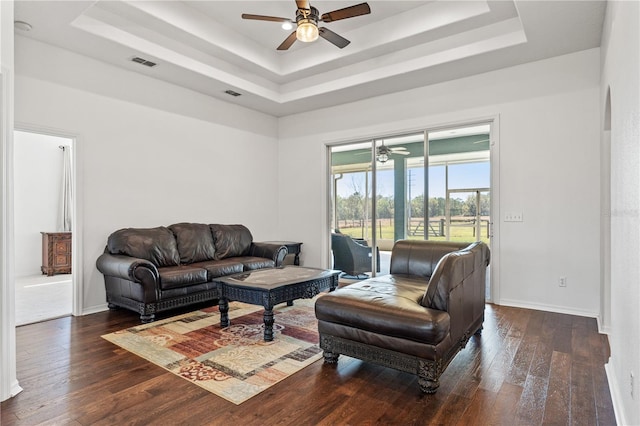 living room with visible vents, a tray ceiling, a ceiling fan, and hardwood / wood-style floors